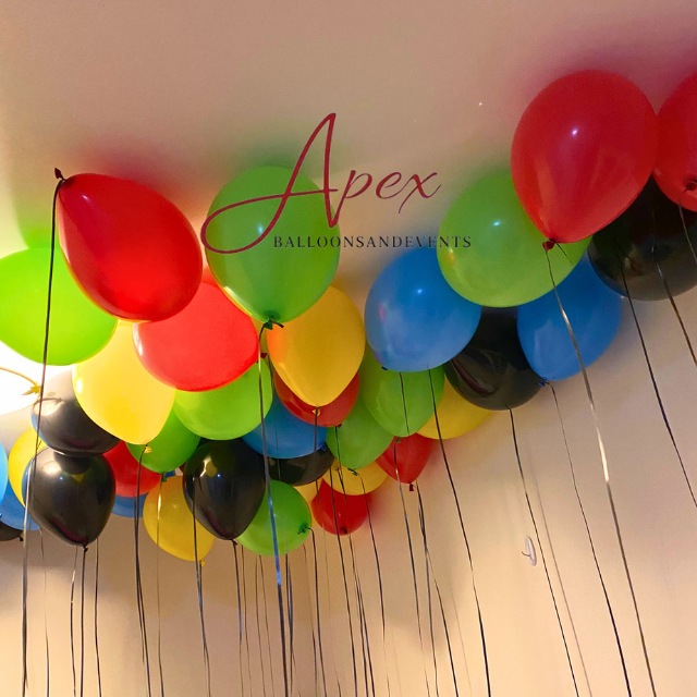 Helium balloons floated individually across a ceiling, with ribbons trailing down